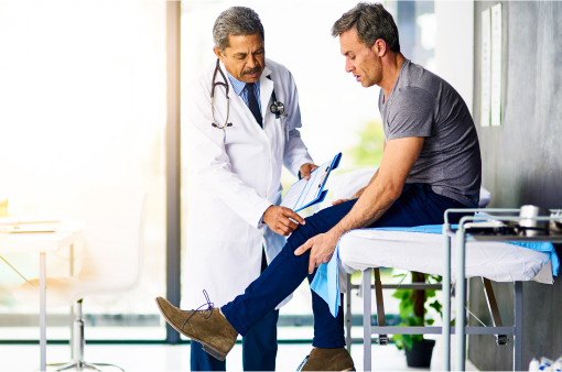Mature doctor examining his patient who is concerned about his knee.