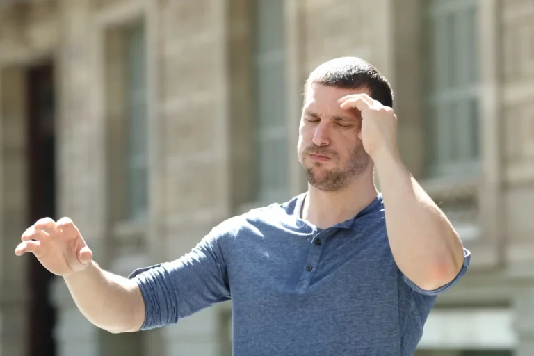 man holding his head from dizziness caused by sneezing from allergies