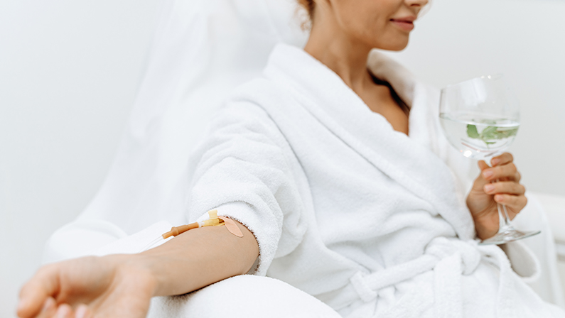 Close up of calm female patient sitting with tube and needle during IV infusion.