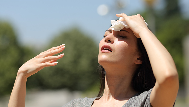 Stressed asian woman drying sweat with a cloth in a warm summer day