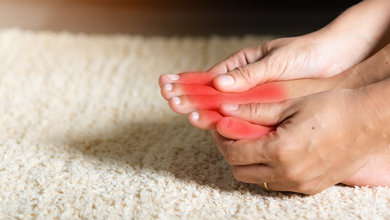 Asian woman holds her toe injury feeling pain her foot at home.