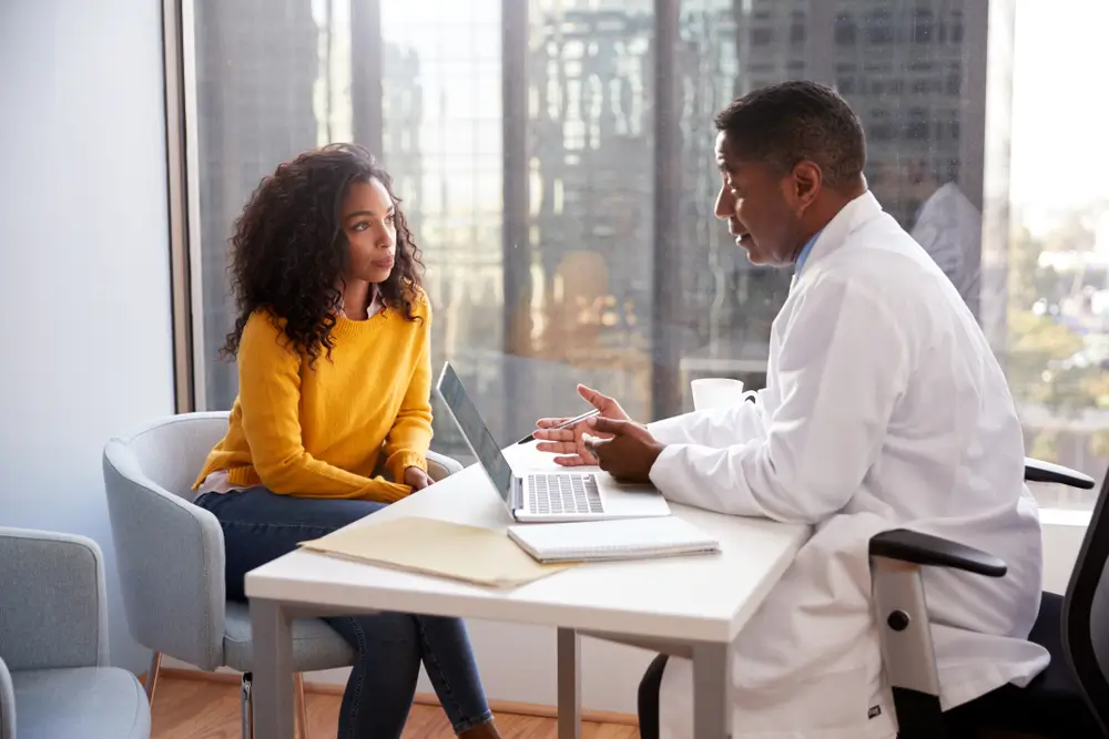 Serious Woman Having Consultation With Male Doctor In Hospital Office