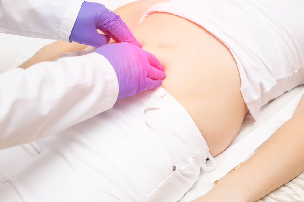 The doctor probes the lower abdomen in a girl who has pain and inflammation of the bladder. The concept of diseases in girls cystitis, kidney stones, dysmenorrhea