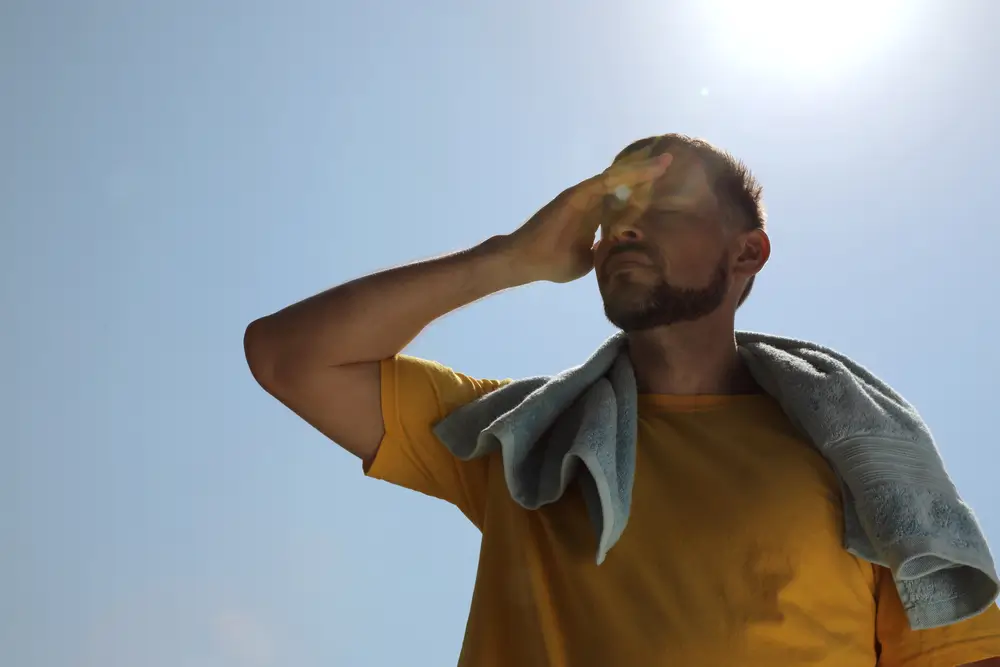 Man with towel suffering from heat stroke outdoors