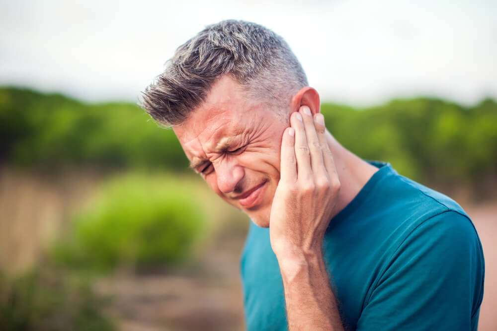 Man with earache is holding his aching ear body pain concept