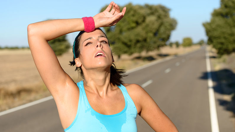 Exhausted sweaty woman after marathon training on hot summer.