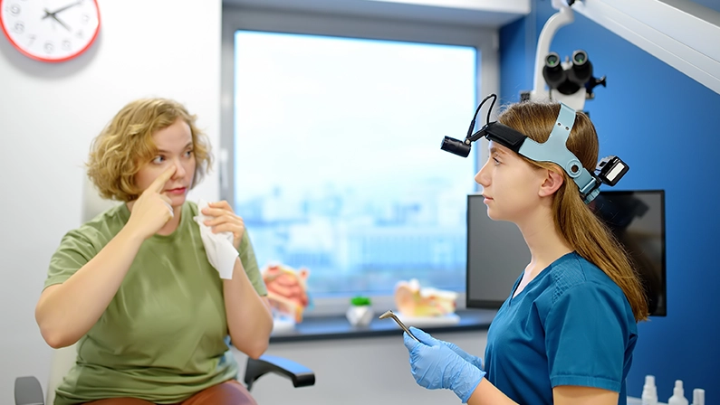 A young woman at an appointment with an otolaryngologist talks about her symptoms. A professional ENT doctor examines a patient. Sinusitis is complications of viral diseases