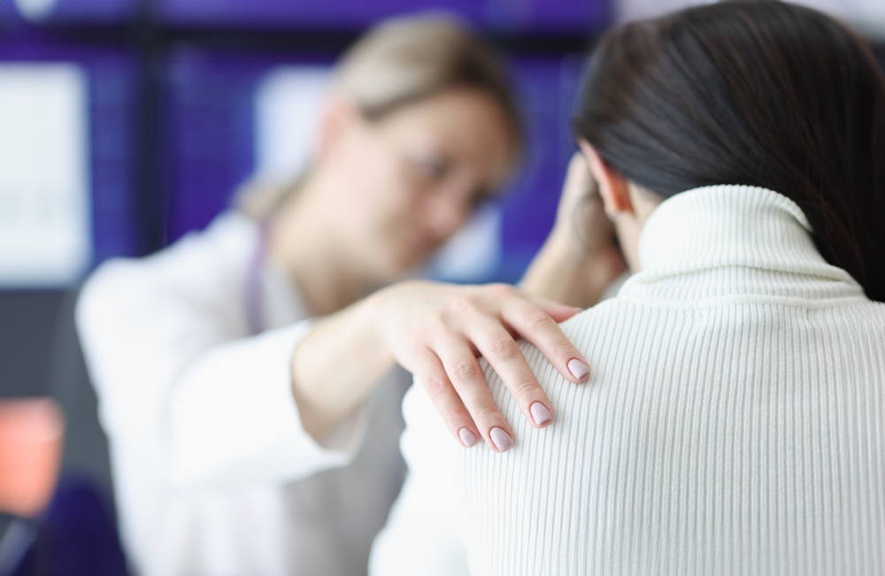 Physician holds upset patient's shoulder sympathetically.