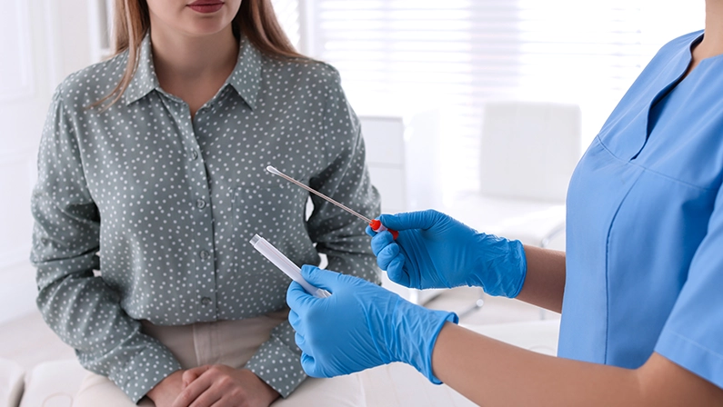 Doctor taking sample for STD testing from woman in clinic, closeup