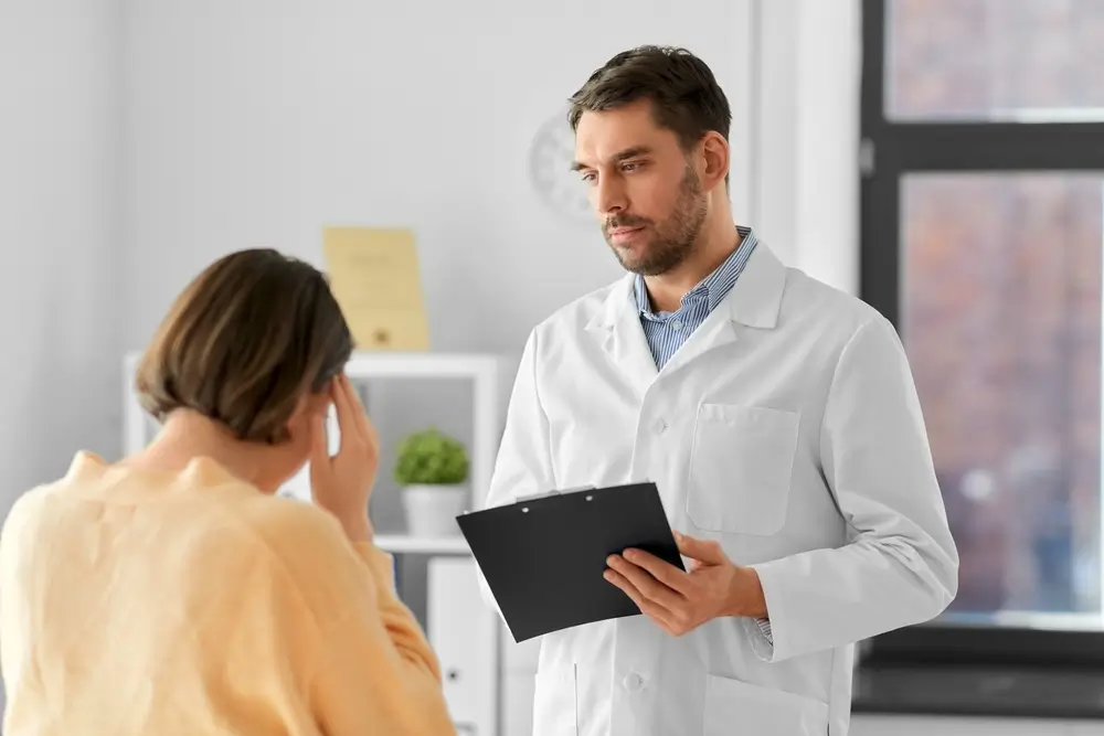 medicine, healthcare and people concept - male doctor with clipboard and fe male patient having health problem at hospital
